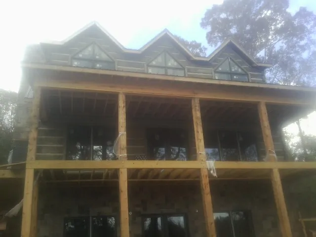 Dormers and porch framing on a large log home under construction — Roof Coating work by our crew in Sperry